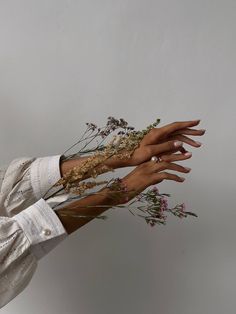 a woman's hands with flowers in her left hand, on a white background