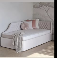 a white bed with pink pillows on top of it and a tree mural behind it