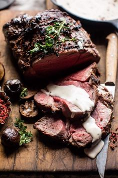 a piece of roast beef on a cutting board next to mushrooms and other food items