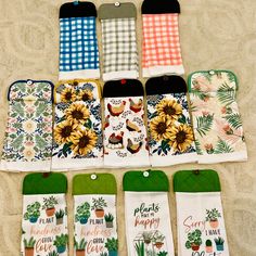 six oven mitts are laid out on the sand with sunflowers and plants