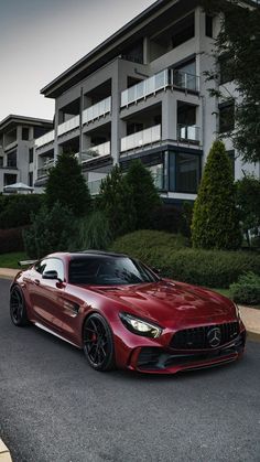 a red mercedes sports car parked in front of an apartment building