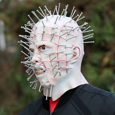 a man with white makeup and spiked hair is wearing a mask made out of wires