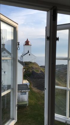 an open window looking out at a lighthouse