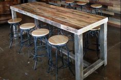 a wooden table with four stools next to it in a room filled with tables and chairs