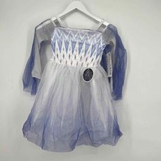 a white and blue dress hanging up on a hanger with a button in it