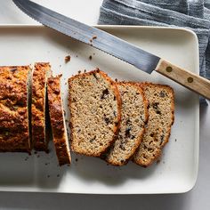 slices of banana bread on a white plate with a knife next to the sliced loaf