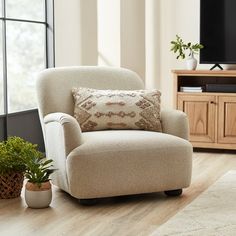 a living room with a couch, chair and television on the stand in front of a large window