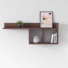 a shelf with some books and a potted plant on it next to a white wall