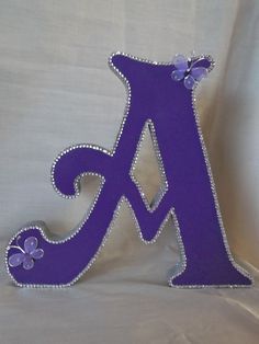 the letter k is decorated with purple and silver beads on it's sides, along with butterflies