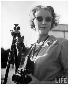 an old photo of a woman holding a camera