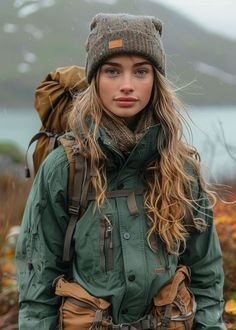 a woman with long hair wearing a green jacket and brown hat standing in the rain