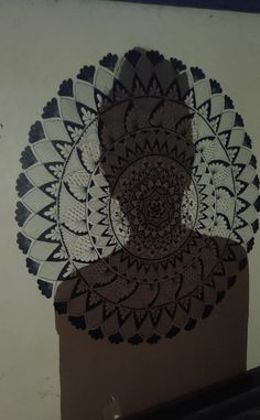 the shadow of a person in front of a doily pattern on a white wall