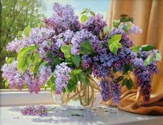 a vase filled with purple flowers sitting on top of a table next to a window