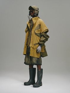 a mannequin dressed in yellow raincoat and rubber boots, standing against a gray background