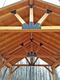 a wooden covered structure in the middle of a forest