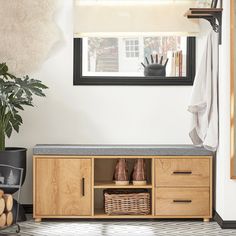 a room with a bench and some baskets on the floor next to a potted plant