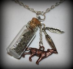 a necklace with a bottle filled with sand and a dog charm