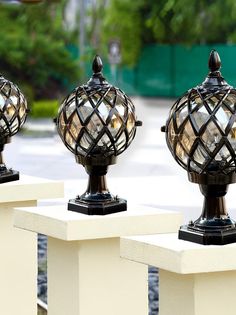 three decorative lamps sitting on top of white posts