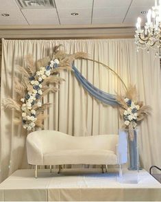 a white couch sitting under a chandelier next to a table with flowers on it