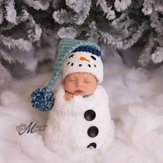 a newborn snowman wearing a hat and sleeping in the snow with his eyes closed