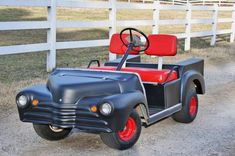 an old style golf cart parked in front of a white fence