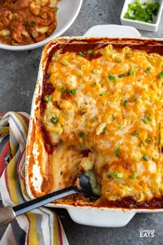 a casserole dish with meat and cheese in it on a table next to other dishes