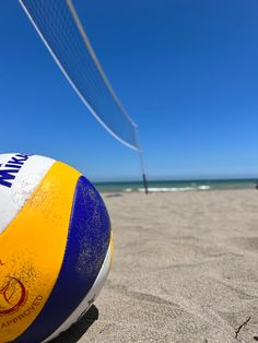 a beach ball on the sand with a net in the background