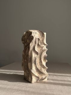 a white vase sitting on top of a table next to a gray wall and floor