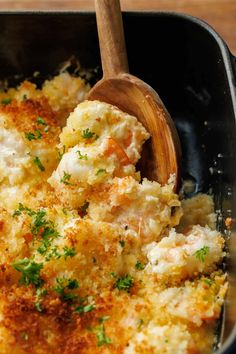 a casserole dish with shrimp and cheese in a black pan on a wooden table