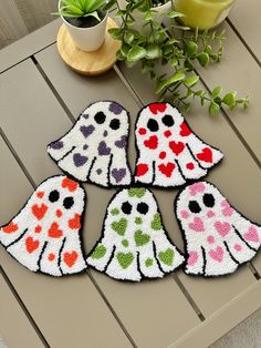 four halloween ghost rugs sitting on top of a table next to a potted plant