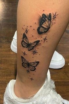 a woman's thigh with two butterflies on it and stars in the sky above