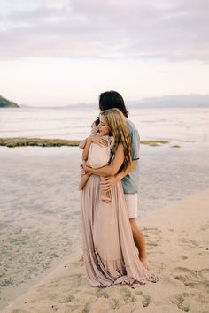 a man and woman hugging on the beach