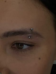 a man with piercings on his forehead looking at the camera