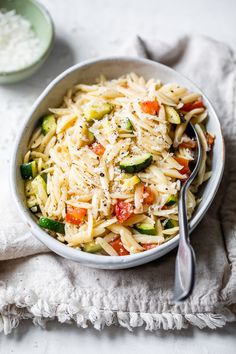 a bowl filled with pasta and vegetables on top of a white towel next to two bowls