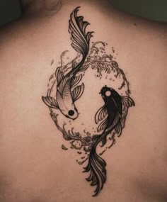 the back of a woman's shoulder with two koi fish on it