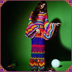 a woman in a colorful crochet dress standing next to a golf ball on a green background