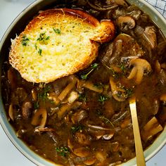 a bowl filled with mushroom soup and a piece of bread on top of the stew