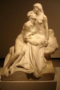 a statue of a woman holding a baby in her lap and kissing the man's head