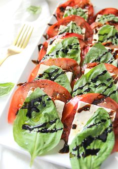 a white plate topped with lots of sliced tomatoes and cheese on top of lettuce