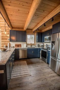 a kitchen with stainless steel appliances and blue cabinets in a log cabin style home on the shores of lake michigan