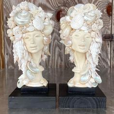 two ceramic head sculptures with shells and seashells on them