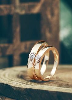 two gold wedding rings sitting on top of a wooden table