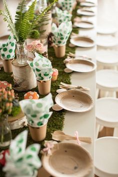 a long table with plates and vases on top of it, decorated with green polka dot paper