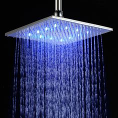 an overhead shower head with blue lights on the side and water running down it's sides