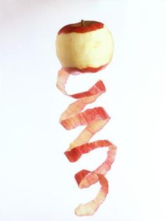 an apple sliced in half and being held by a string with bacon on it to eat