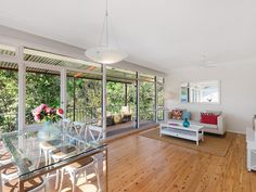 a living room filled with white furniture and lots of glass doors leading to an outside deck