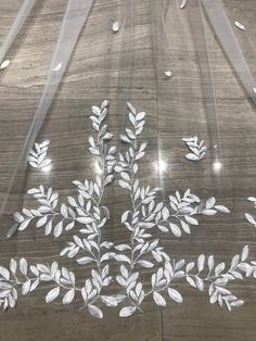 a white flower and leaf design on a clear plastic covering over a wooden table top