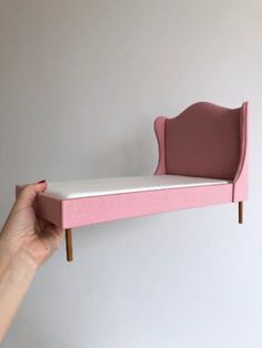 a person holding up a pink and white bed with two legs on the bottom half of it