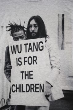 a man holding a sign that says wu tang is for the children