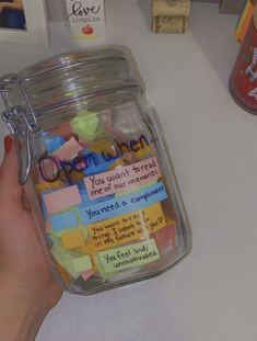 a person holding a jar with sticky notes on it and magnets attached to the lid